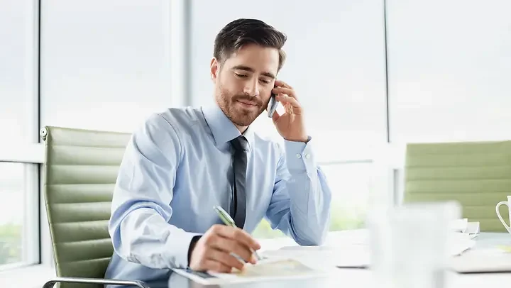 Angestellter am Schreibtisch beim Telefonat: PKV-Beitrag mit Arbeitgeberzuschuss